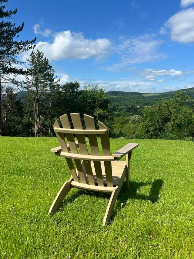 Wooden garden chair on a lawn facing a green mountain valley